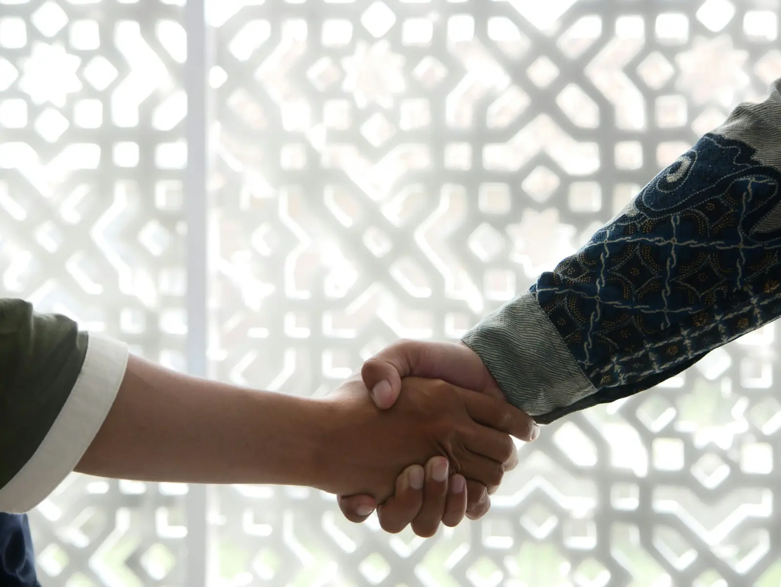 Handshake in front of a mashrabiya