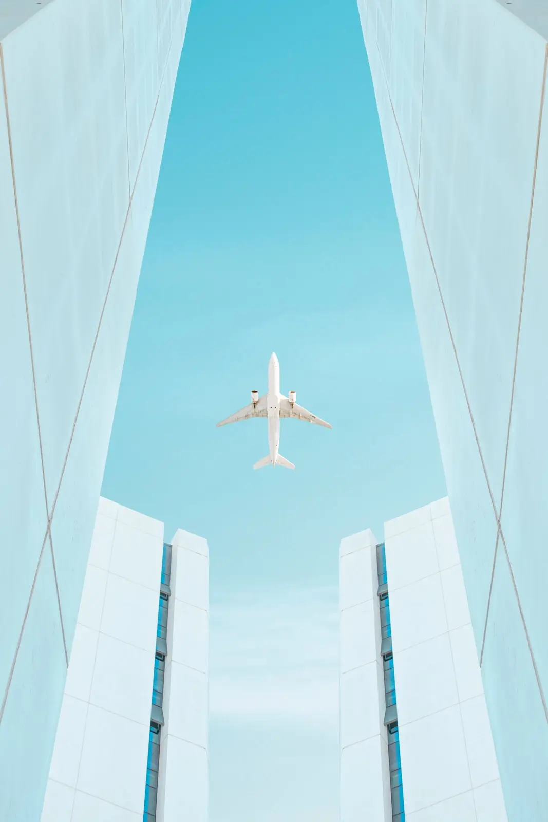 Avion entre deux immeubles blancs, ciel bleu